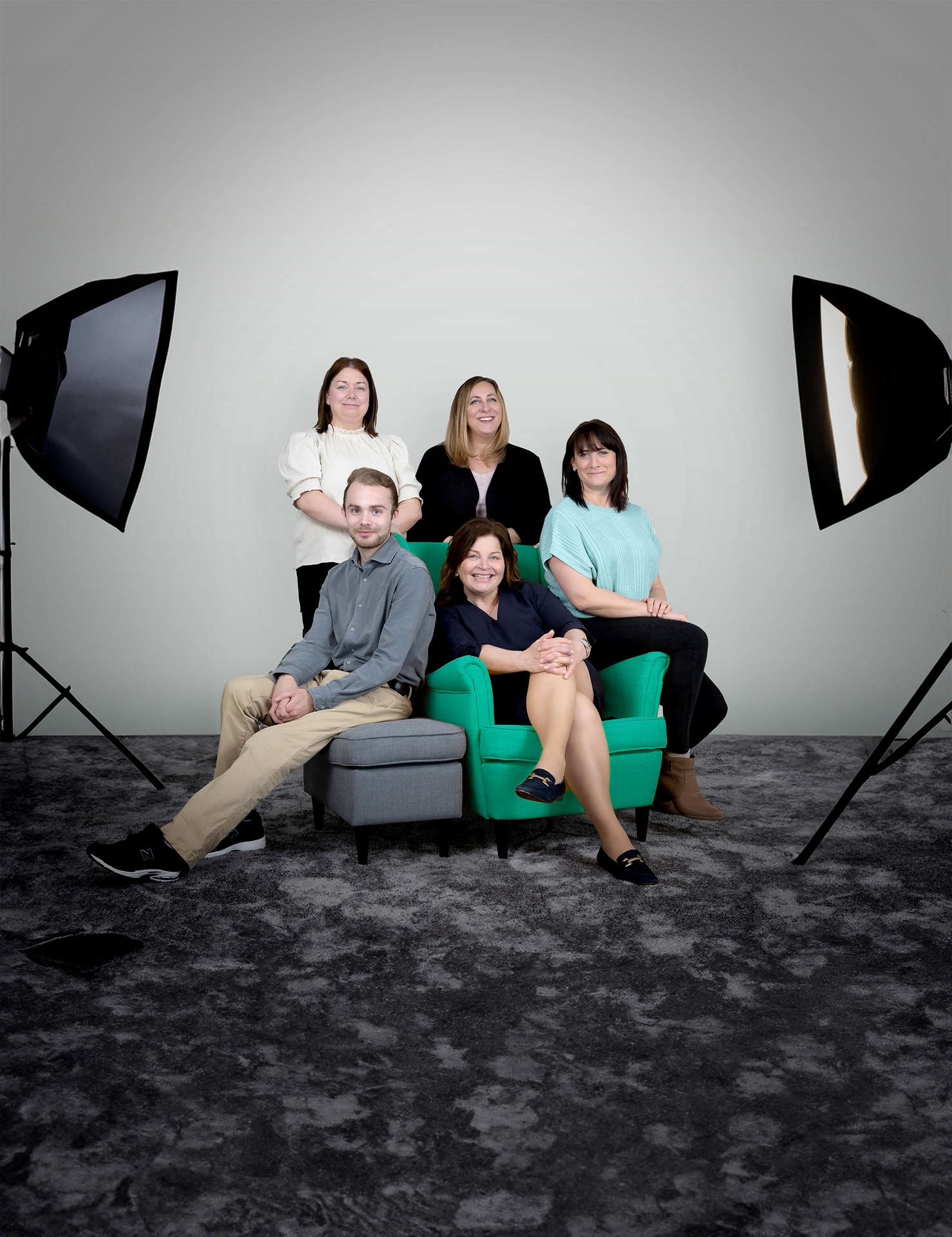 Gruppporträtt i studio med synliga softboxar runt en grön fåtölj